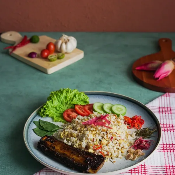 Nasi Goreng Achiera, fried rice plated with something grilled, fresh vegetables and sambal.