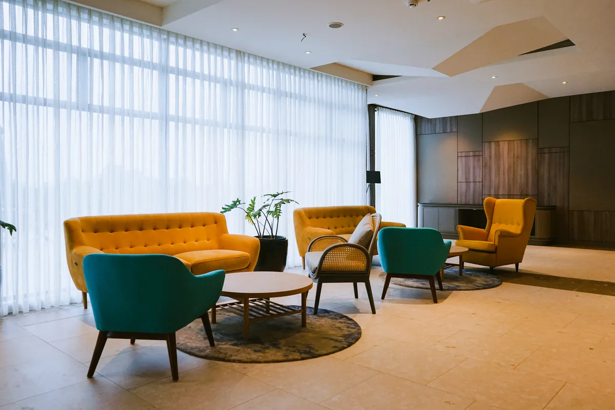 The prefunction lounge, deep armchairs against a wall of sheer curtain.