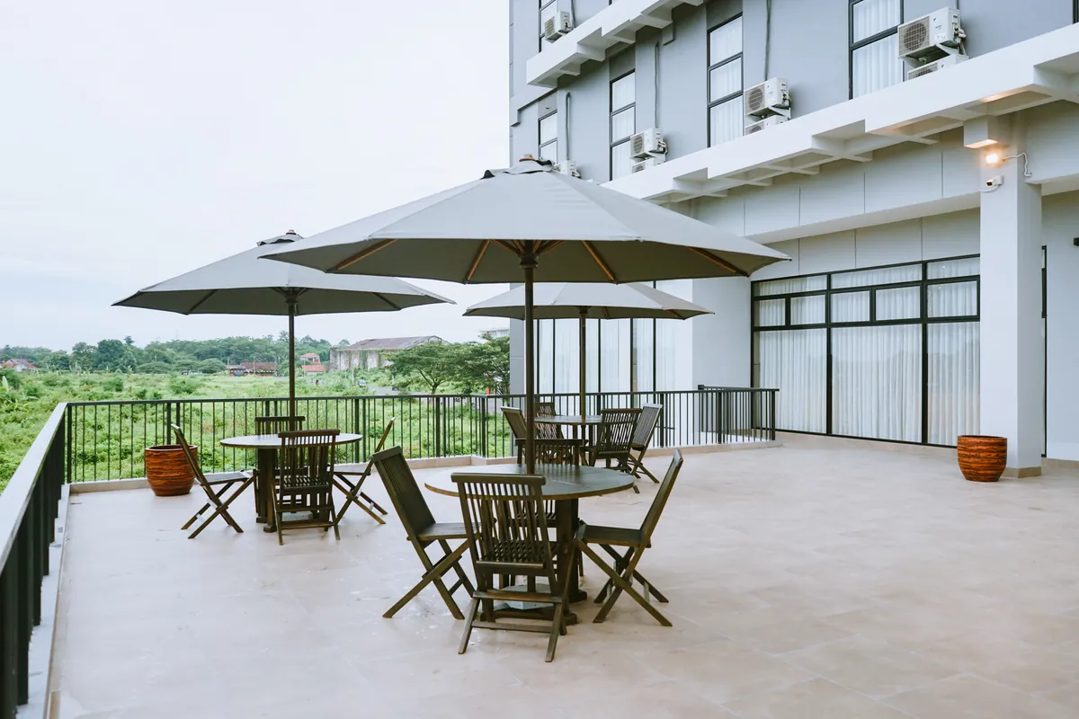 The terrace beside the function floor, teak tables under parasols looking over the fields.