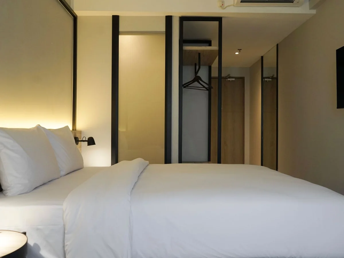 A Premium Superior room: double bed against the lit headboard, with the wardrobe and entry beyond.
