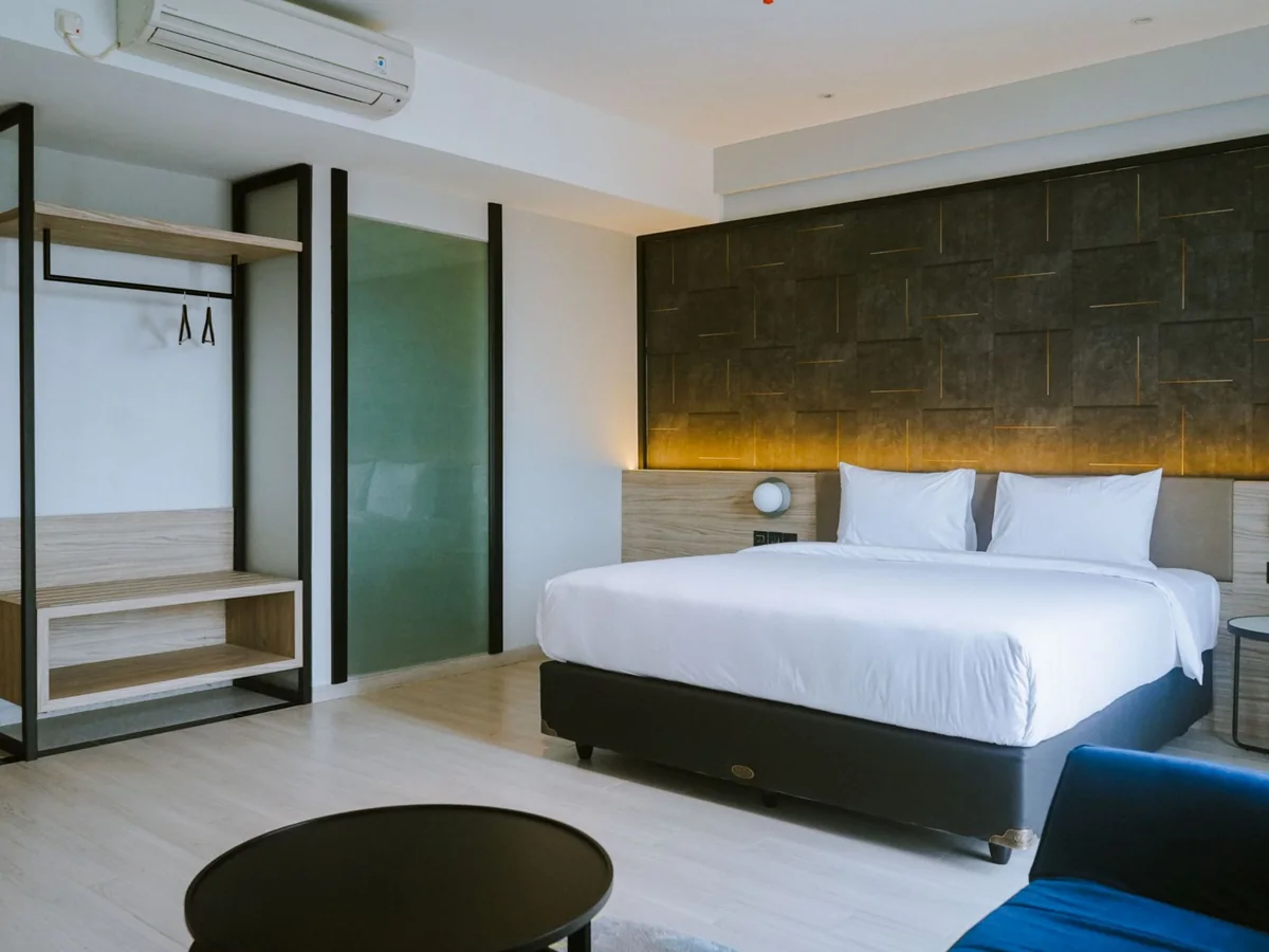 A Suite with a king bed, open wardrobe, round table and its own sofa.